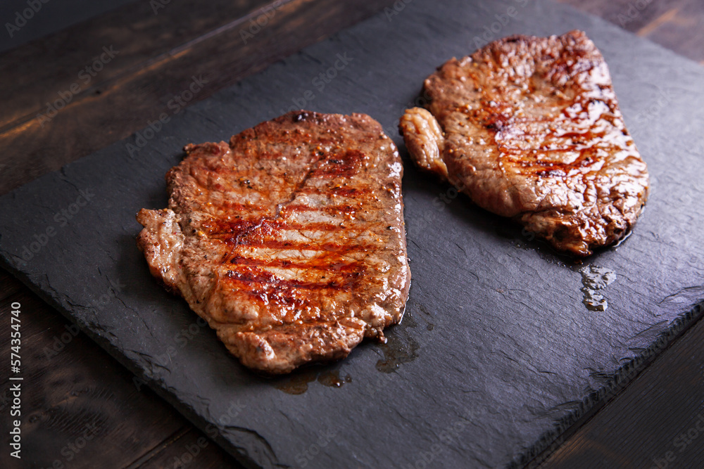 Grilled minute steak of marbled beef on a stone slate board, close up