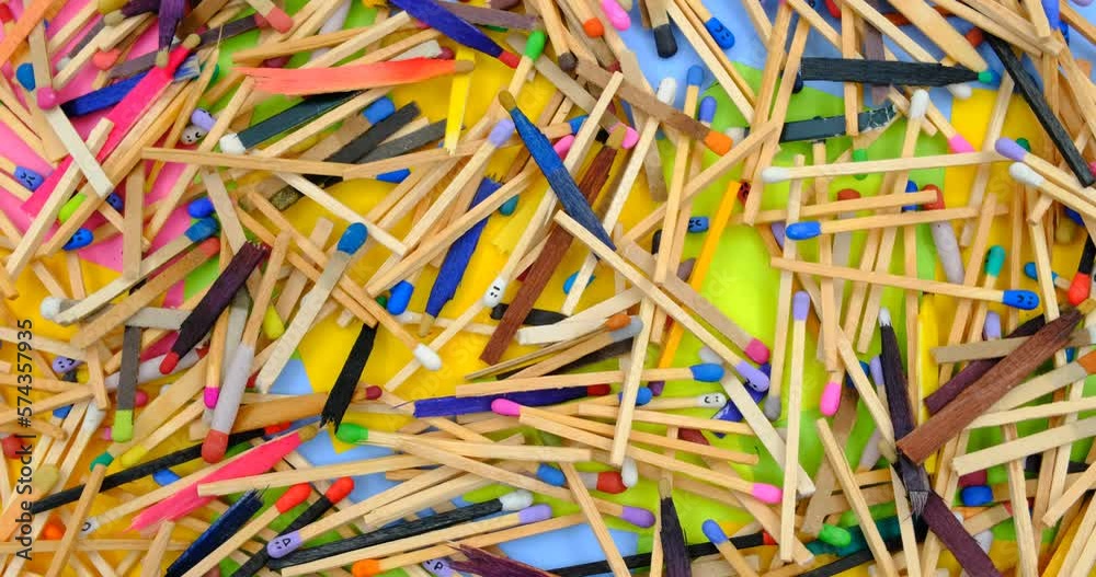 matchsticks of various shapes and colors on a rotating table with multicolored paper sticky notes on background