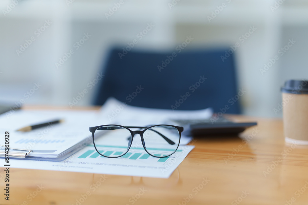 Desk of bookkeeper with balance sheet and calculator on desk, focused on eyeglass, nobody. Desk of bookkeeper with balance sheet and calculator on desk, focused on eyeglass, nobody.