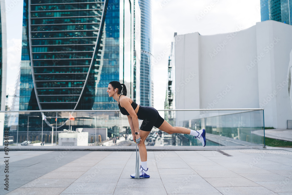 Athletic woman doing exercises on street with tape