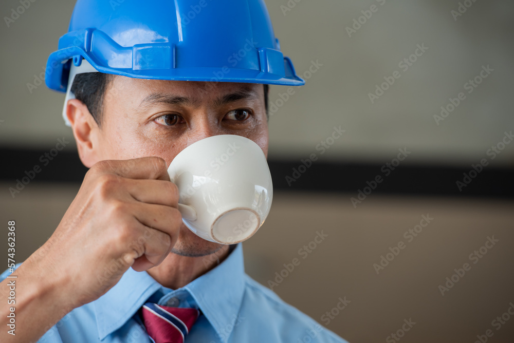 engineer with blue helmet and shirt hurry urgency urgency donut fast food and coffee at lunch meal time. Worker busy hurry bite donut junk fast food in working site.