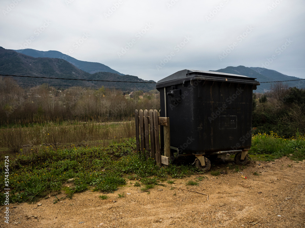 imagen de un contenedor al lado de un camino de tierra, con una valla de madera para evitar su movimiento, con las montañas de fondo y el cielo nublado imagen de un contenedor al lado de un camino de tierra, con una valla de madera para evitar su movimiento, con las montañas de fondo y el cielo nublado