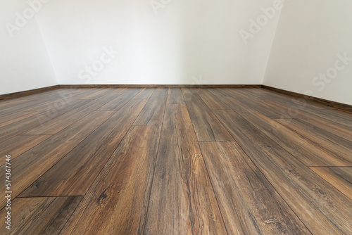 Laminated wood floor with white wall. Empty room with floating laminate in new apartmen © dechevm