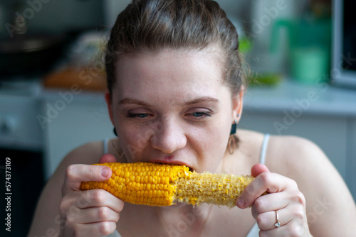 The girl greedily eats boiled corn. Yellow, bright, freshly cooked corn at home. The concept of live real photos. woman eating delicious corncob.