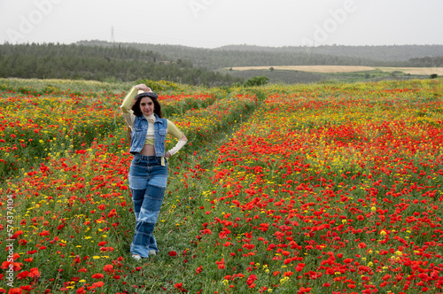 Attractive young woman wearing red dress walking happy in poppy flower spring field. Springtime Cyprus