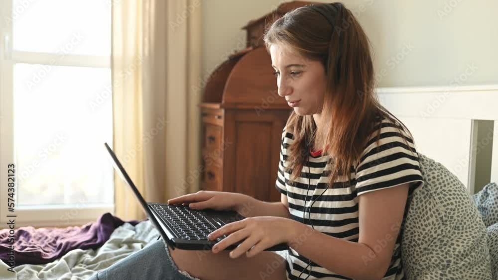 Pretty girl with headphones and laptop in bed