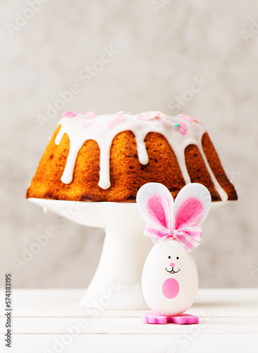 Easter composition with funny bunny, Easter decor and Easter cake on a festive background