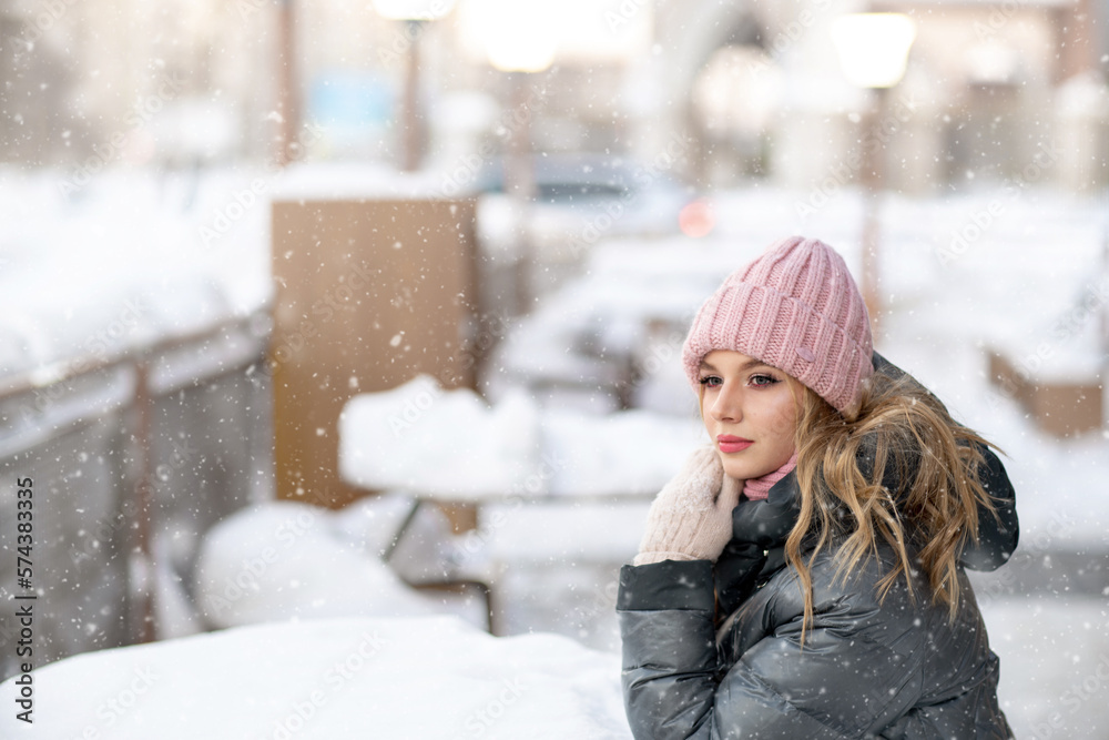 Outdoor portrait of a young beautiful happy smiling girl with long hair in a pink cap, scarf posing on a snowy street. Copy, empty space for text. High quality photo Outdoor portrait of a young beautiful happy smiling girl with long hair in a pink cap, scarf posing on a snowy street. Copy, empty space for text. High quality photo
