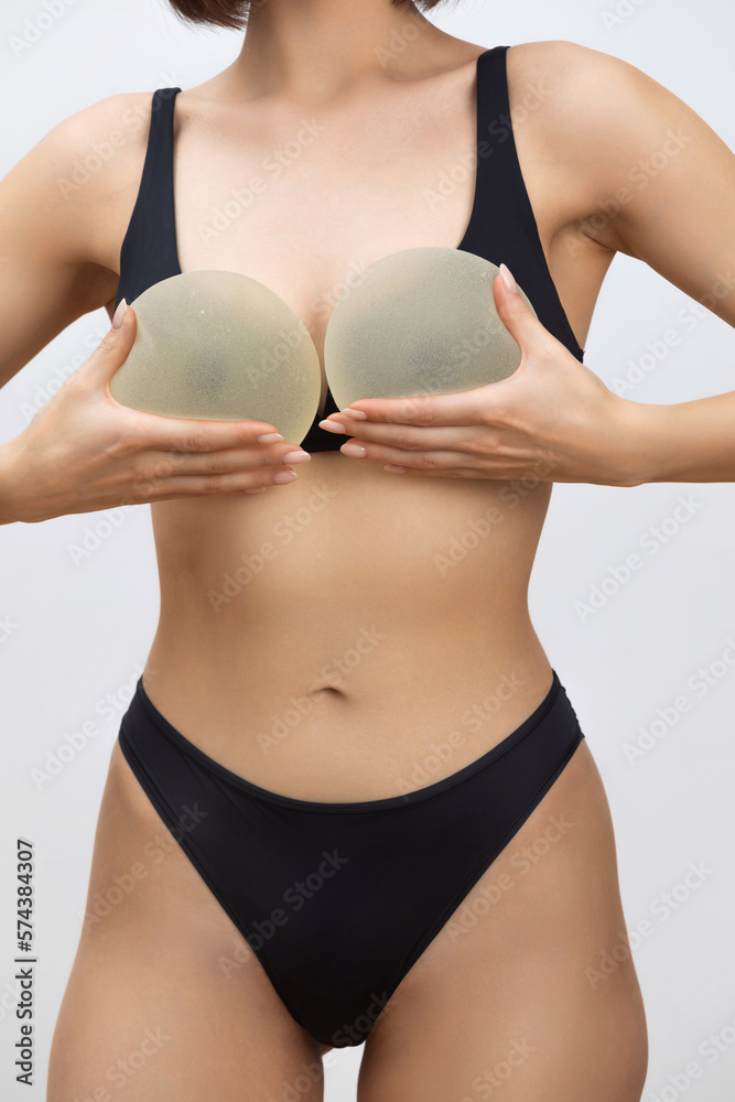 Close up of female body - beauty industry and cosmetic plastic surgery concept. Woman holding silicone breast implant for breast augmentation