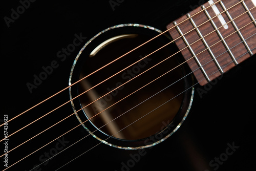 Guitar sound hole and strings shot from above in flat lay style. Beautiful black acoustic guitar in close up