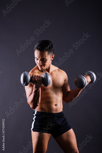 Portrait young fitness sporty strong man bare-chested muscular sportsman isolated on grey dark. © Ivan Zelenin