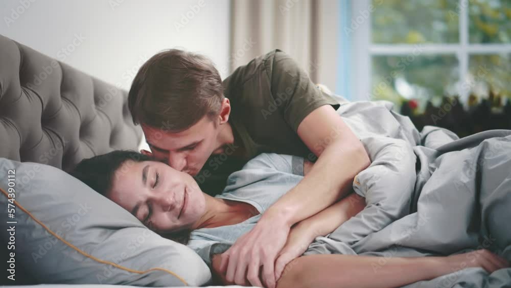 Young man wake up and kiss sleeping wife in bed. Realtime