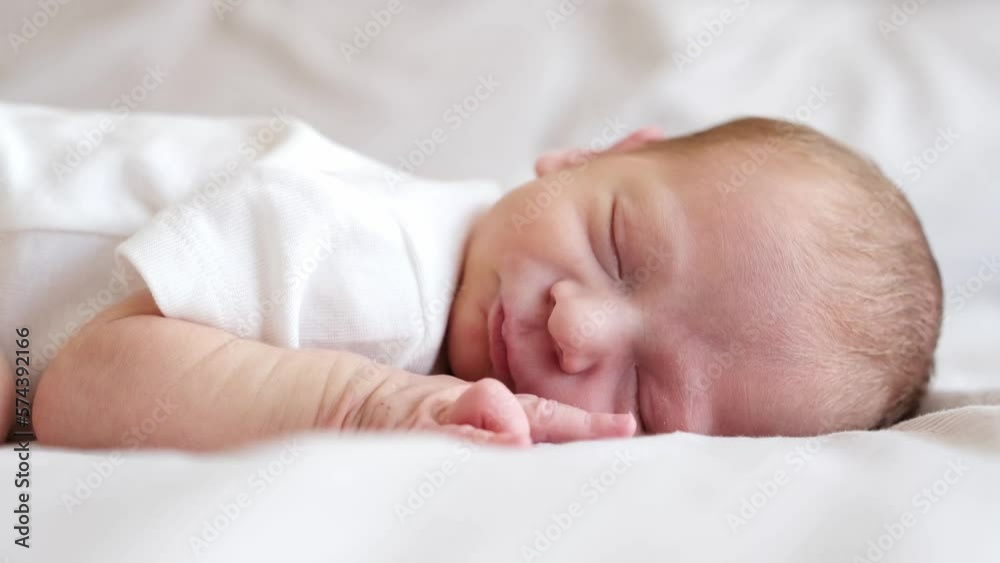 Cute adorable newborn baby boy lying on stomach on white bed at home sleeping,Purity,innosence concept.Half body shot.Close-up.Side view.