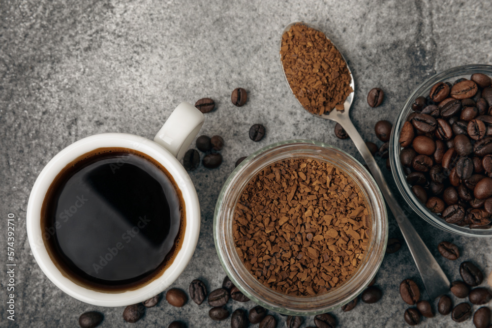 instant coffee. Instant instant coffee powder with a teaspoon in a transparent glass jar and black espresso coffee in a white ceramic bowl on a black concrete background. Energy drink. instant coffee. Instant instant coffee powder with a teaspoon in a transparent glass jar and black espresso coffee in a white ceramic bowl on a black concrete background. Energy drink.