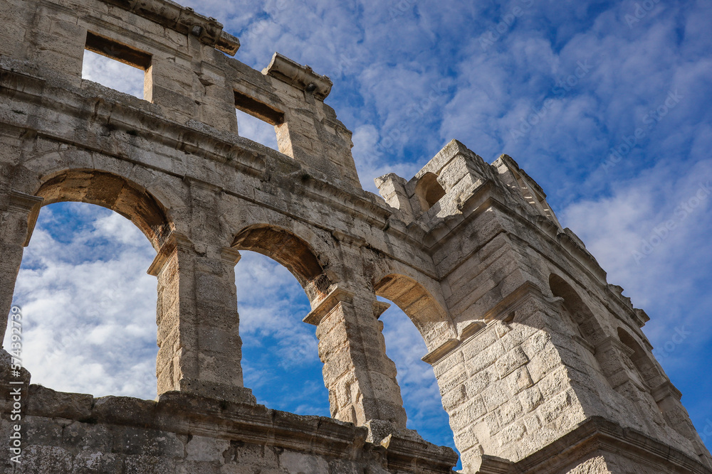 Historic Pula Arena in Istria. Beautiful Roman Amphitheatre with Arch and Blue Sky with Clouds in Croatia.