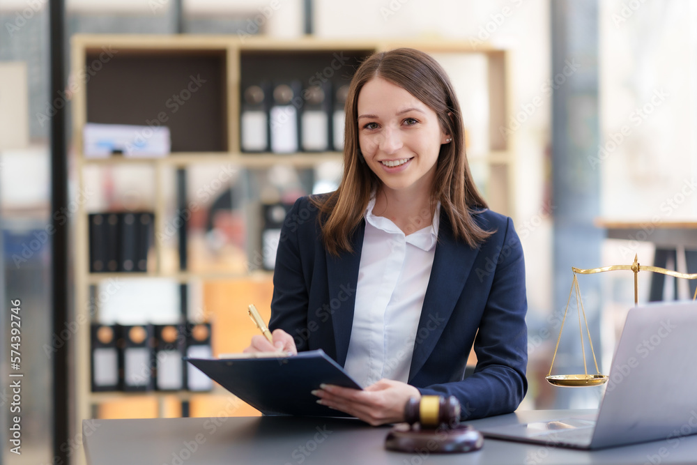 Female lawyer sitting happily working on laptop computer with hammer and legal book scales. Female lawyer sitting happily working on laptop computer with hammer and legal book scales.