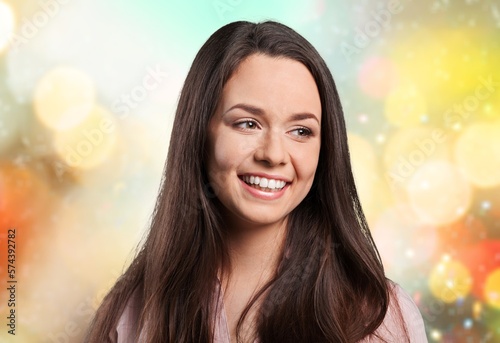Smiling young woman with long hair posing on background