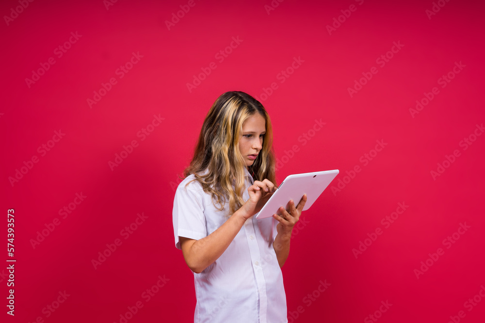 Online school app. Schoolgirl showing tablet computer Empty Screen Over red Background. Studio Shot Online school app. Schoolgirl showing tablet computer Empty Screen Over red Background. Studio Shot