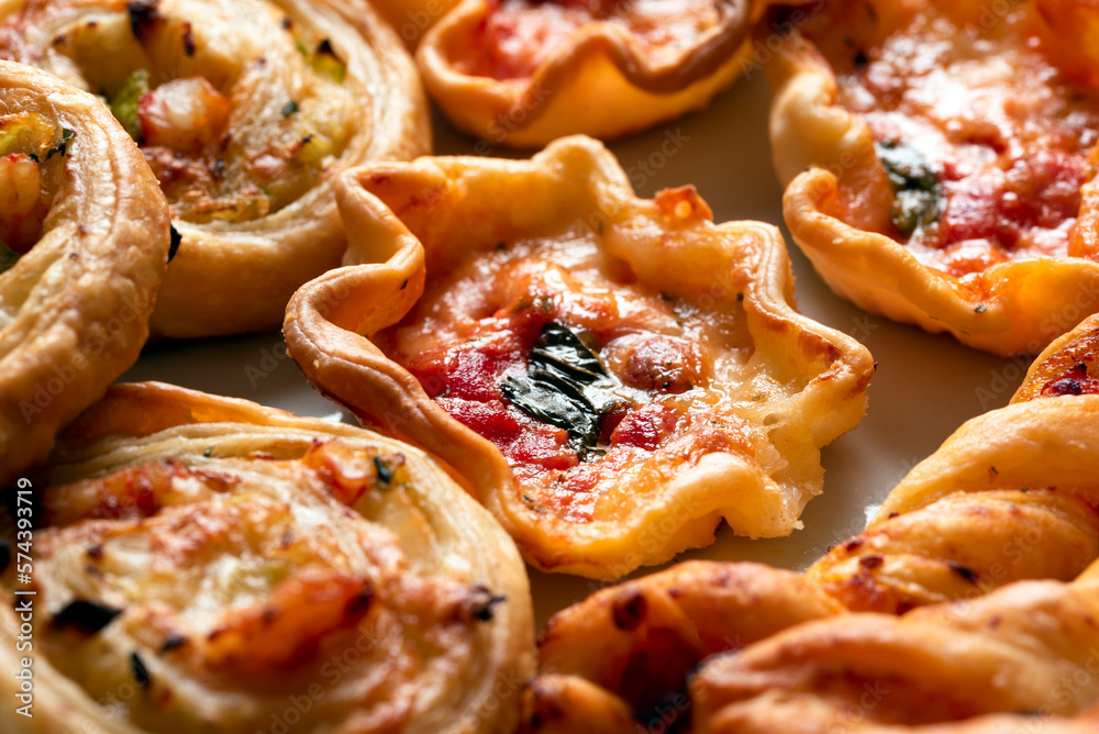Piatto con manicaretti di pasta sfoglia conditi con mozzarella, pomodoro e pancetta, antipasto italiano 