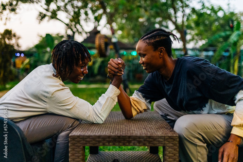 Two queer masculine women arm wrestling in a garden