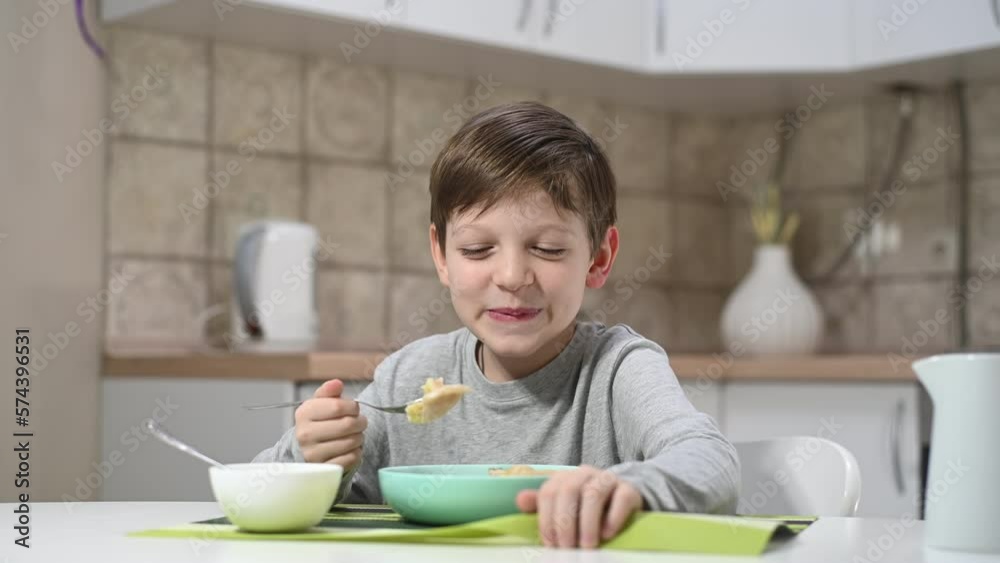 Boy enjoys a delicious meal of traditional Ukrainian dumplings at dinner table. His eyes light up with pleasure as he savors each bite, savoring the rich and comforting flavors of home-cooked food. Boy enjoys a delicious meal of traditional Ukrainian dumplings at dinner table. His eyes light up with pleasure as he savors each bite, savoring the rich and comforting flavors of home-cooked food.