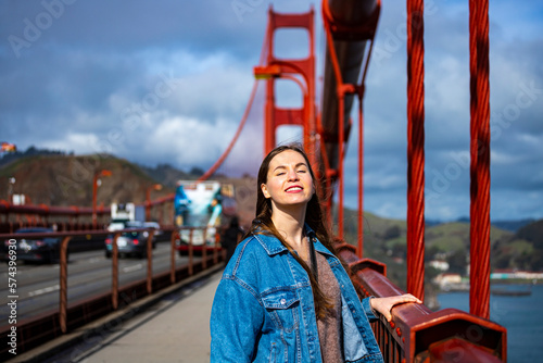 Canvas Print a beautiful long-haired model in a denim jacket stands on the famous golden gate