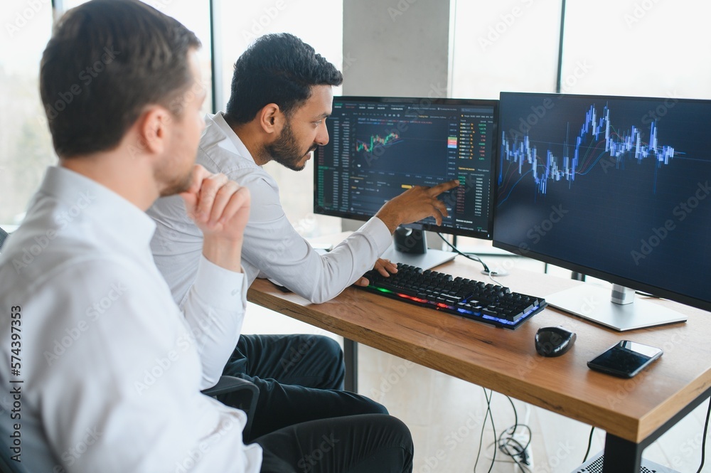 Two diverse crypto traders brokers stock exchange market investors discussing trading charts research reports growth using pc computer looking at screen analyzing invest strategy, financial risks.