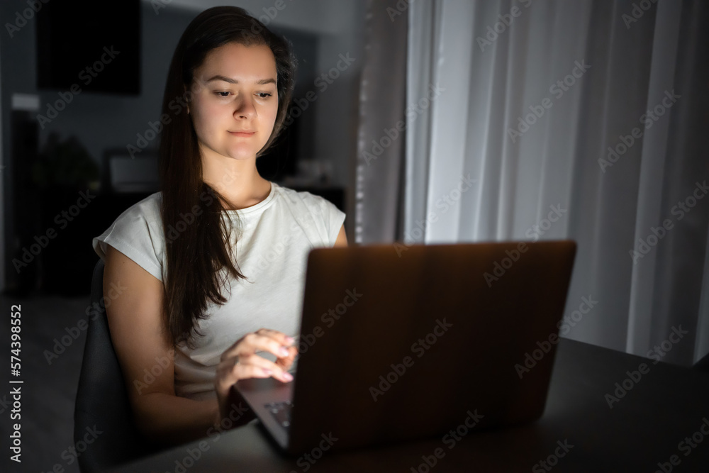 Casual beautiful woman working on a laptop at the night at home. Casual beautiful woman working on a laptop at the night at home.
