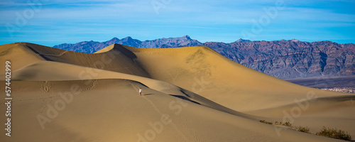 girl in white dress lost in the desert; walking on large sand dunes in mesquite flat sand dunes in death valley national park, california, usa