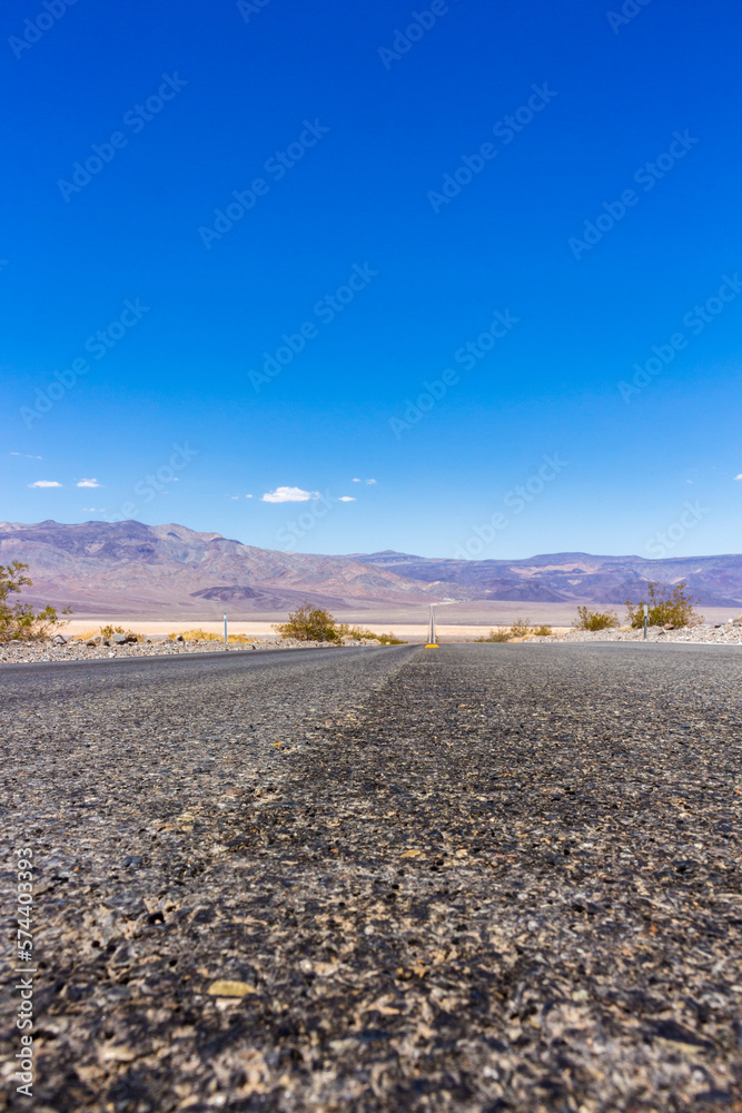 State Route 190 crossing Panamint Valley in Death Valley National Park, California, United States. Empty desert road in Death Valley with clear blue sky.