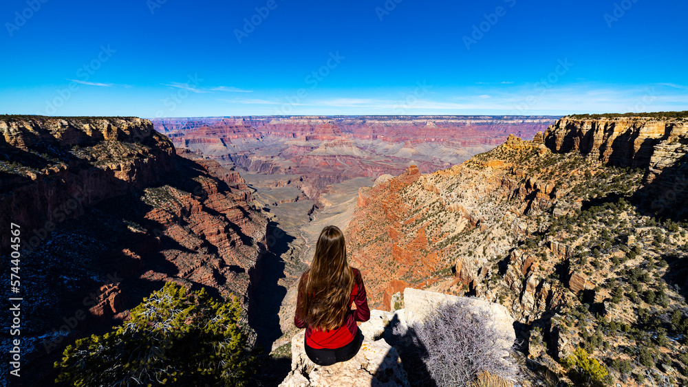 long haired hiker girl sitting on the edge of grand canyon; hiking in ...