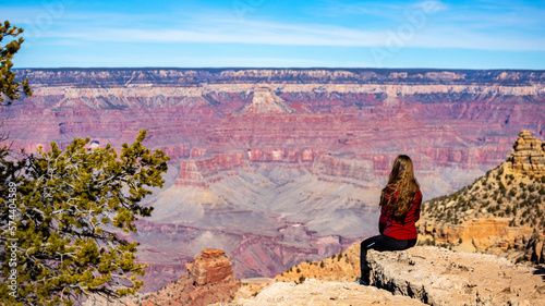 long haired hiker girl sitting on the edge of grand canyon; hiking in the grand canyon national park during spring, spring panorama of grand canyon