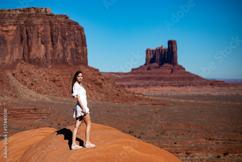Beautiful long-haired girl in white dress on the background of mighty unique rock formations in Monument Valley. Navajo Tribal Park, Utah; Arizona, USA.