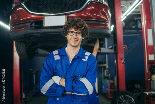 Portrait of smiling male mechanic technician in arms crossed at auto garage. Repair and maintenance after service, Maintenance automotive and inspecting vehicle part concept.