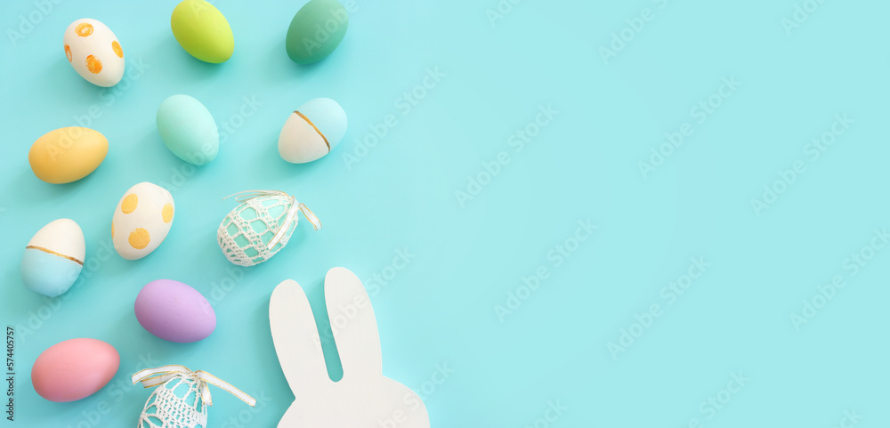 Cute bunny next to easter colorful eggs over blue pastel background Cute bunny next to easter colorful eggs over blue pastel background