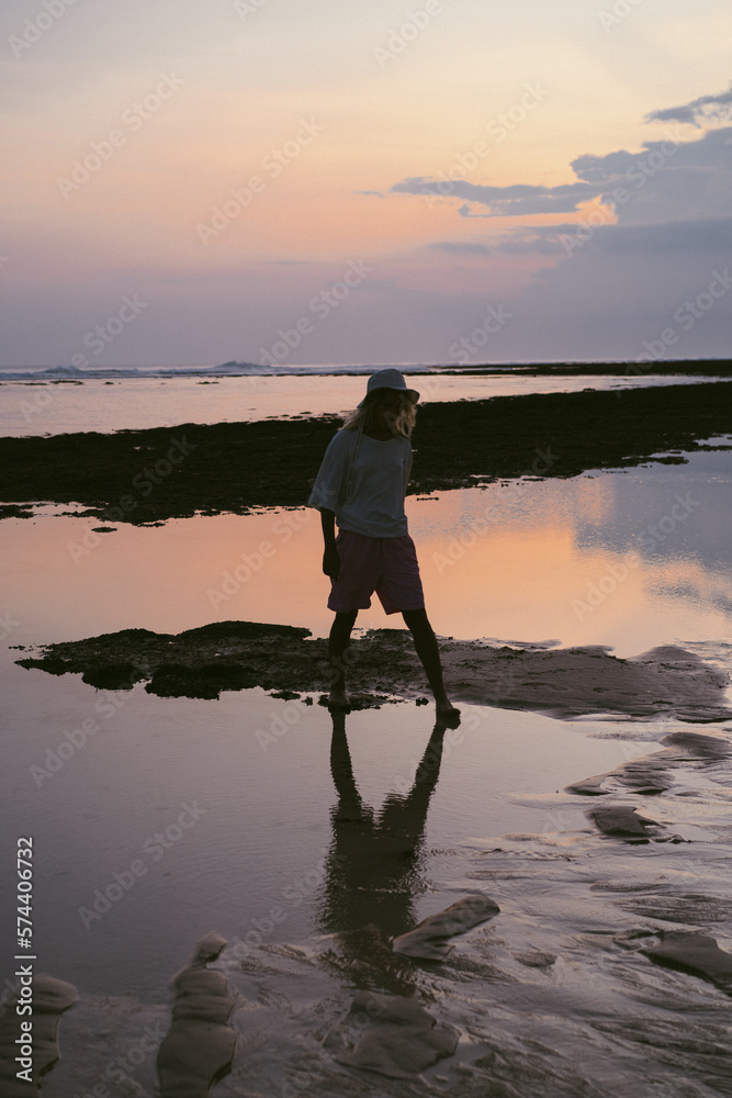 A man on the ocean at sunset, reflected in the water.