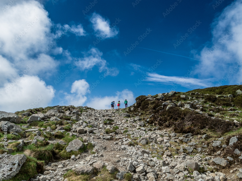Excursionistas subiendo una montaña por un camino rocoso