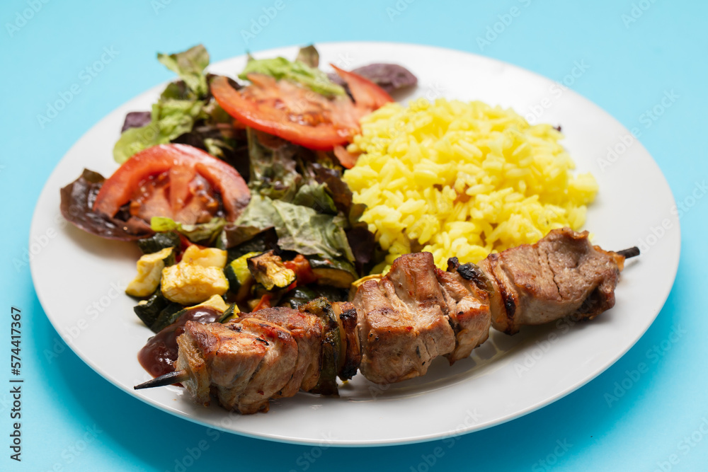 Grilled meat on stick, vegetables, salad and boiled rice