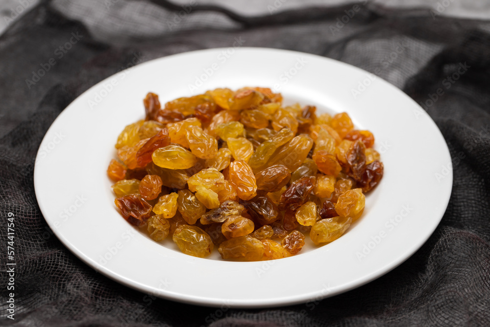 Yellow golden raisins in white ceramic plate Yellow golden raisins in white ceramic plate
