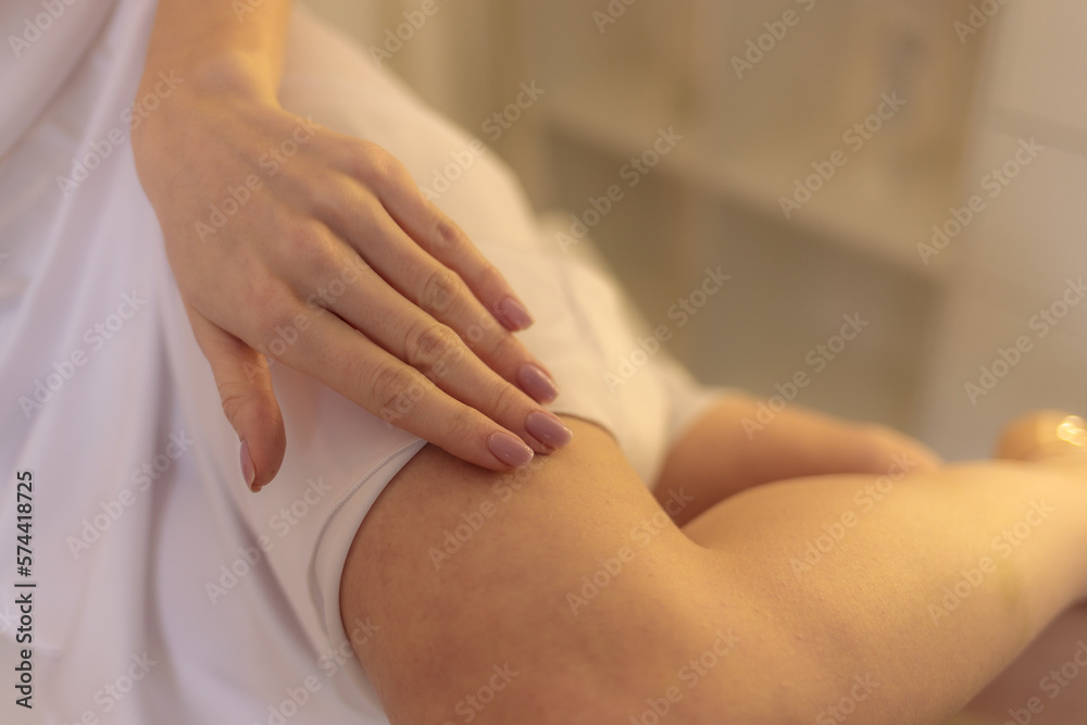 beautiful young fair-haired girl in a long white silk dress posing in a bright dressing room with beautiful flowers
