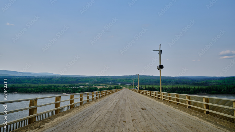 The wood planked Yukon river bridge looking northbound with the Alaska Pipeline off in the distance river