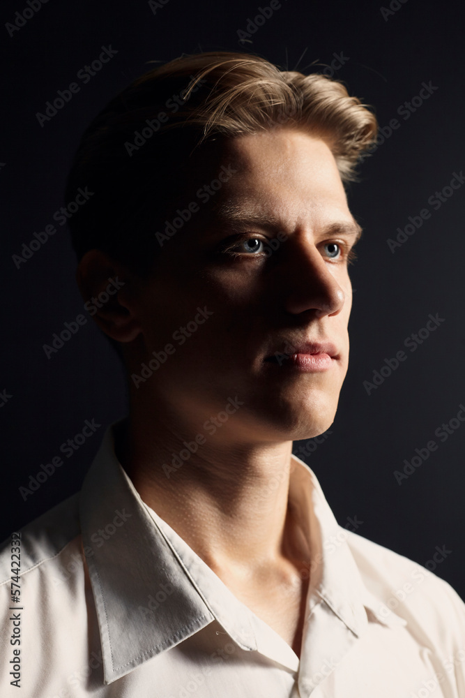 portrait of a handsome man in a white shirt on a black background, looking seriously at the camera portrait of a handsome man in a white shirt on a black background, looking seriously at the camera