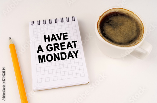 On a white surface, a cup of coffee, a pencil and a notepad with the inscription - Have a great Monday