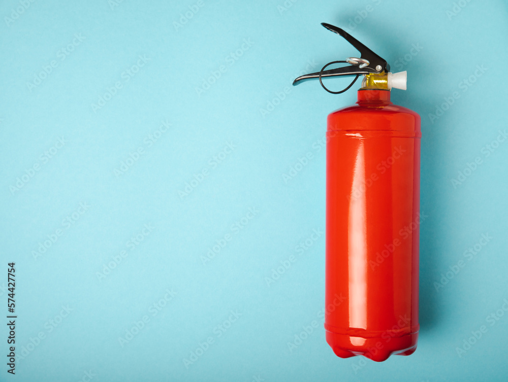 Fire extinguisher on a blue background.Red fire extinguisher indoors on the wall. Fire protection, home fire extinguisher. Mockup, space for text, copy space.