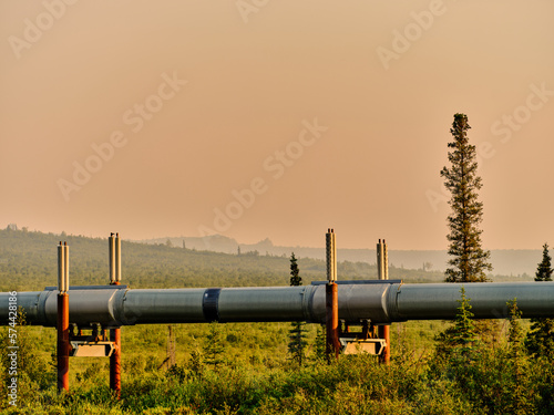 The Trans-Alaska Oil Pipeline travels along the Permafrost and Tundra on it's way south as seen near the North Slope on the approach to Prudhoe bay Alaska seen through the orange sky of nearby fires