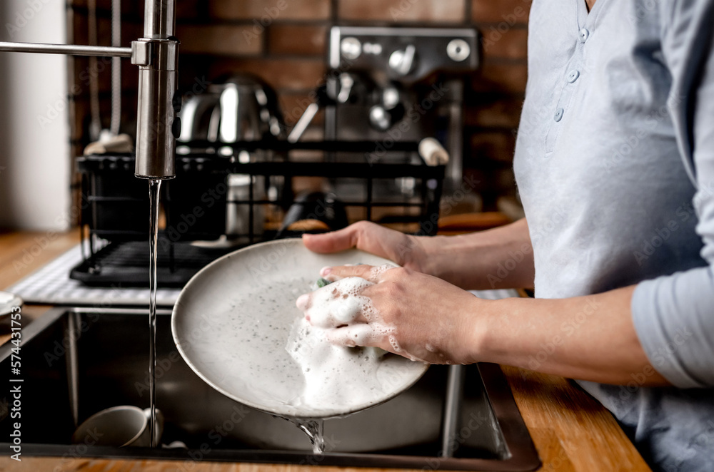Fototapeta premium Girl washing dishes at kitchen at home