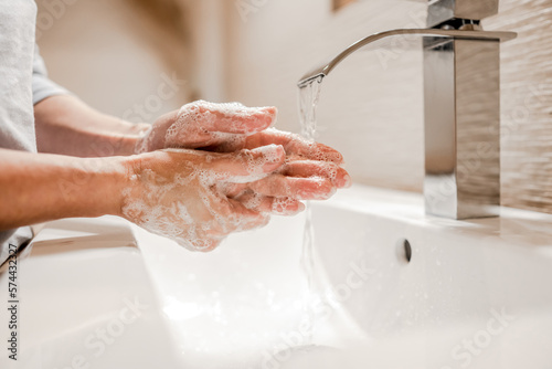 Girl washing hands with soap in bathroom photo