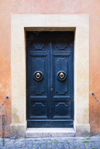 Elegant old blue double door entrance of building in Europe. Vintage wooden doorway of ancient stone house. Simple bright colored wood door with ring door handle. Architecture in Italy.