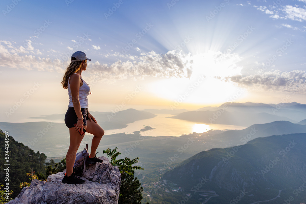 Happy girl with a backpack is on the edge of a high mountain in Montenegro Happy girl with a backpack is on the edge of a high mountain in Montenegro