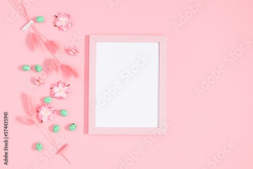Easter decor, composition. Empty photo frame, flowers, easter eggs on pastel pink background. Flat lay, top view, copy space © prime1001